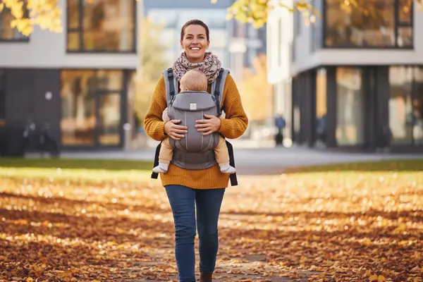 Äiti kantaa vauvaa repussa kaupunkipuistossa — kokemuksia kantamisesta