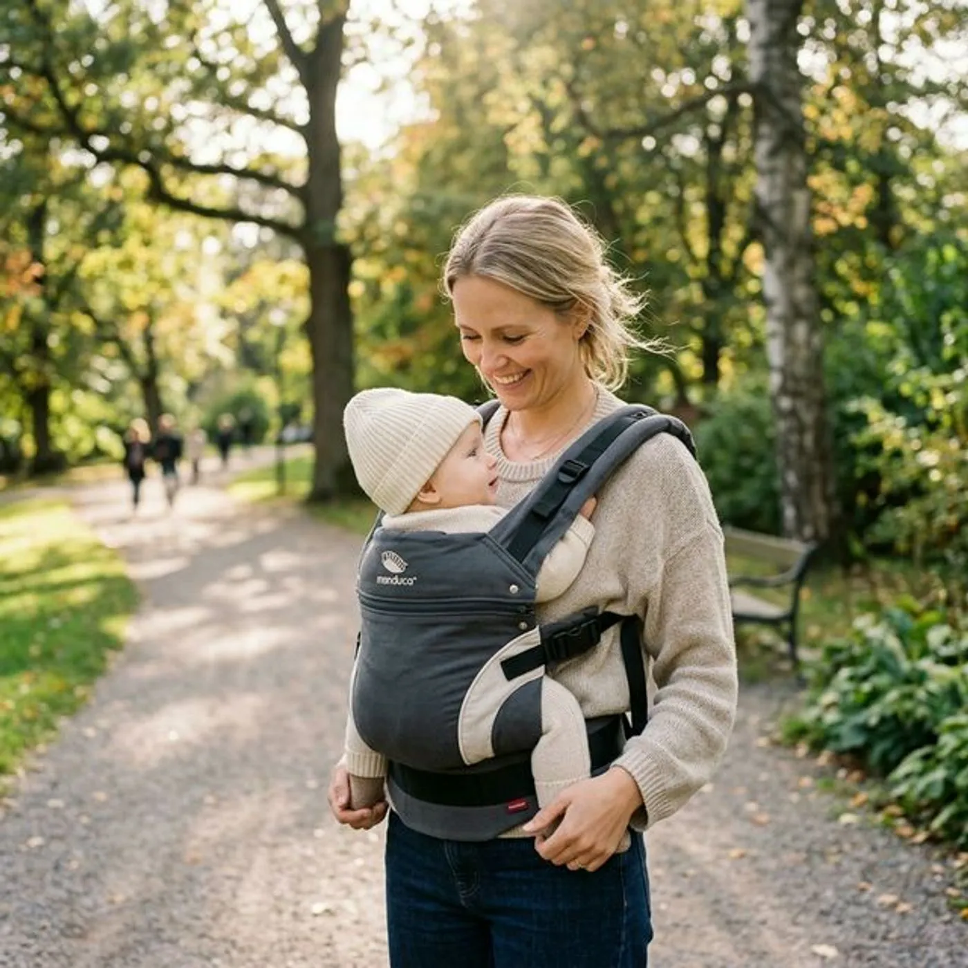 Vanhempi säätää Manduca-kantorepun vyötäröhihnaa M-asennossa olevan vauvan kanssa