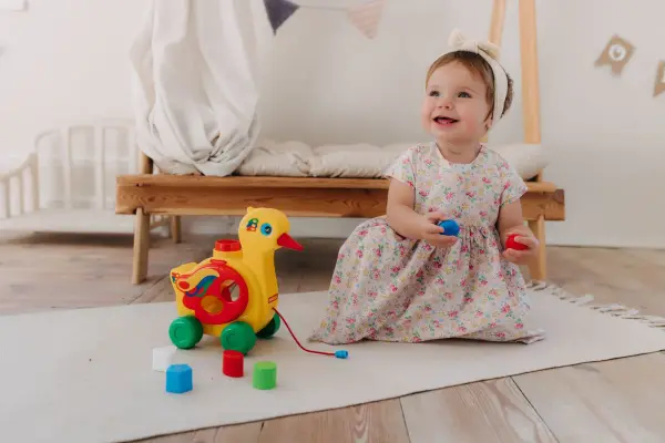 Vauva istuu lattialla ja leikkii lelun kanssa