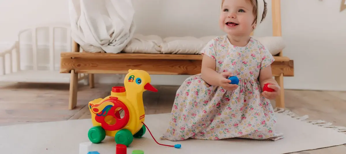 Vauva istuu lattialla ja leikkii lelun kanssa