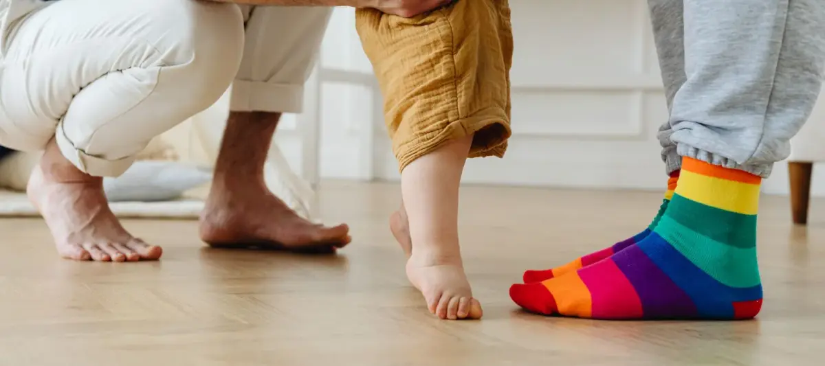 Taapero ottaa ensiaskeleita aikuisen tukemana